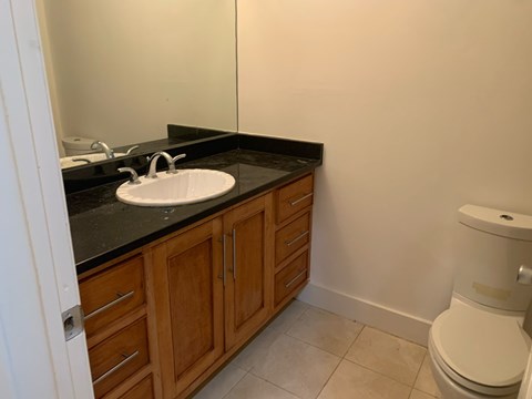 A bathroom with a white toilet and a sink with wooden cabinets.