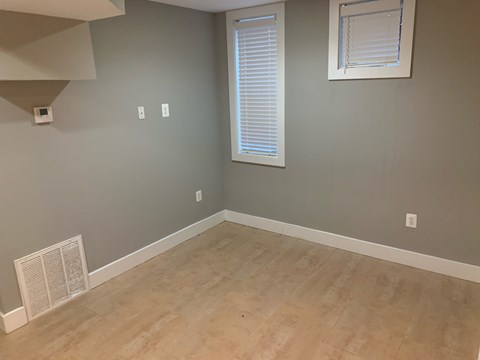 A room with a window and a wall-mounted air vent.