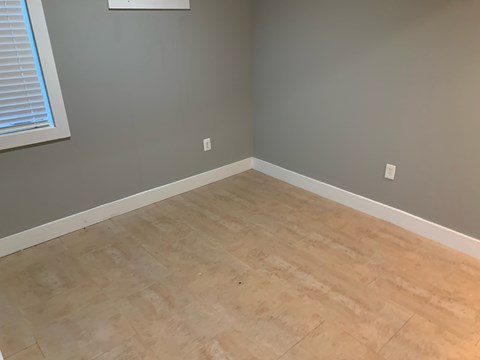 A room with light brown flooring and white trim.