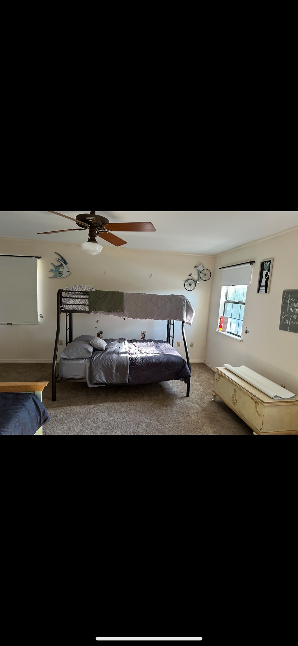 A bedroom with a bed, a ceiling fan, and a window.