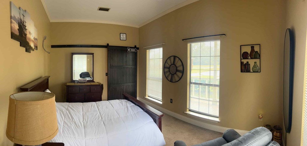 A bedroom with a bed, dresser, and window.