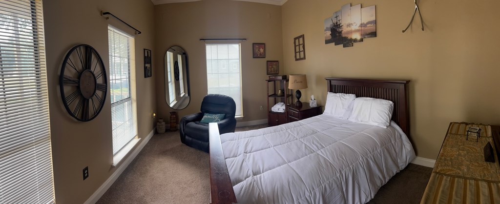 A bedroom with a bed, chair, and a clock on the wall.