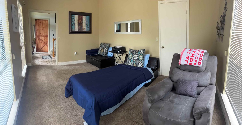 A living room with a grey couch and a blue bedspread.