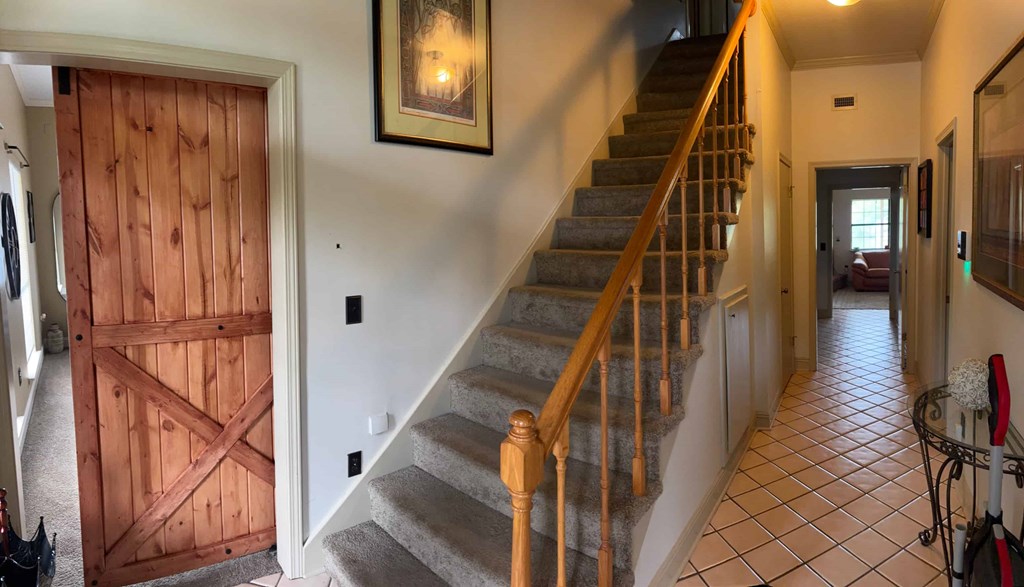 A hallway with a staircase and a wooden door.