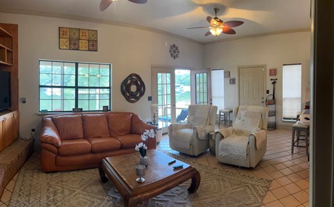 A living room with a brown leather couch and white armchairs.