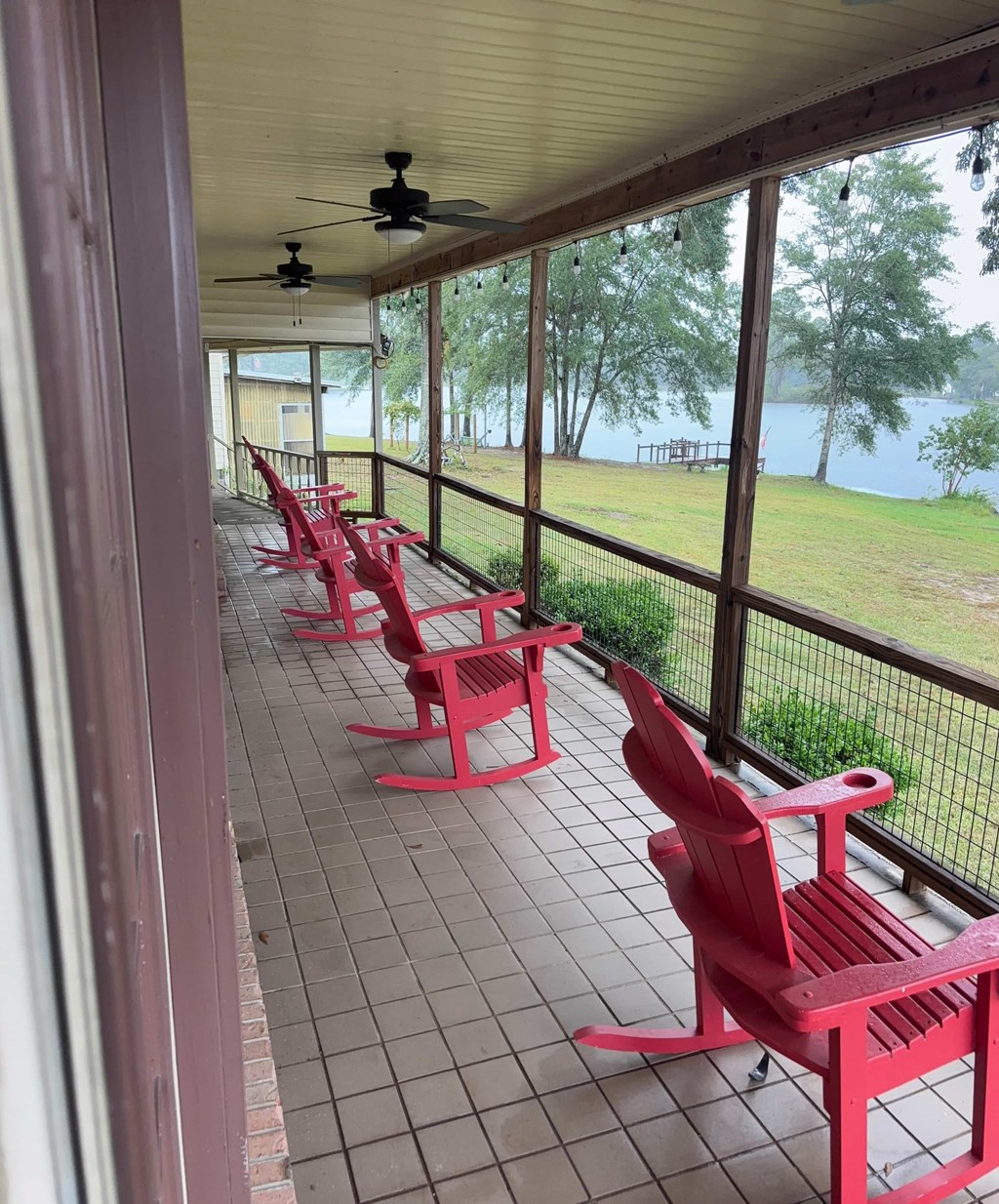 A row of red chairs are on a patio overlooking a lake.