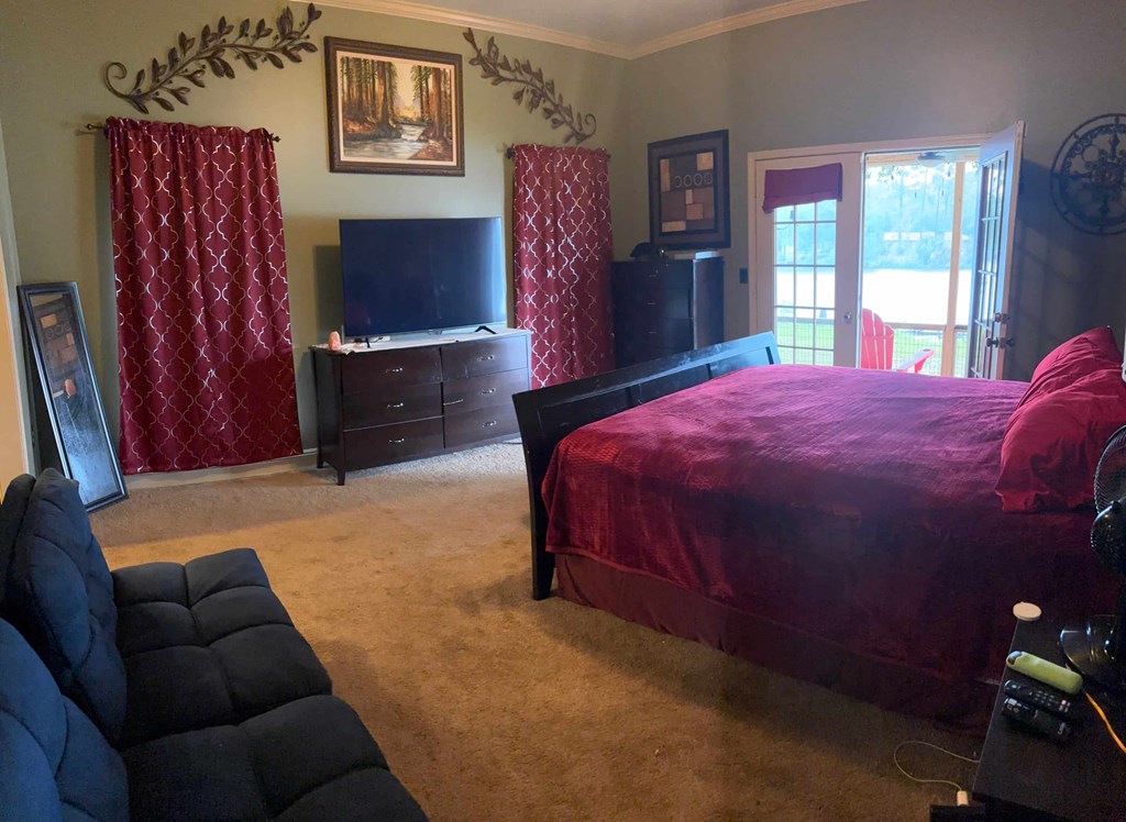 A bedroom with a red bedspread and a television.
