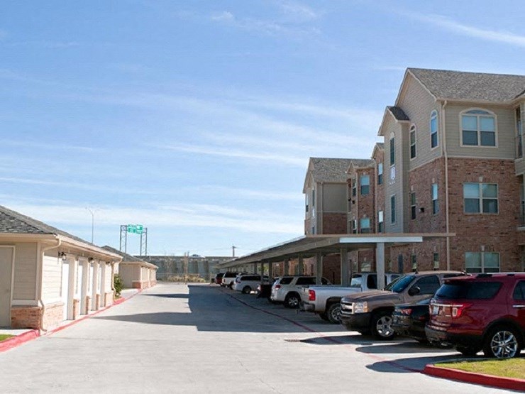A parking lot with cars and apartment buildings in the background.