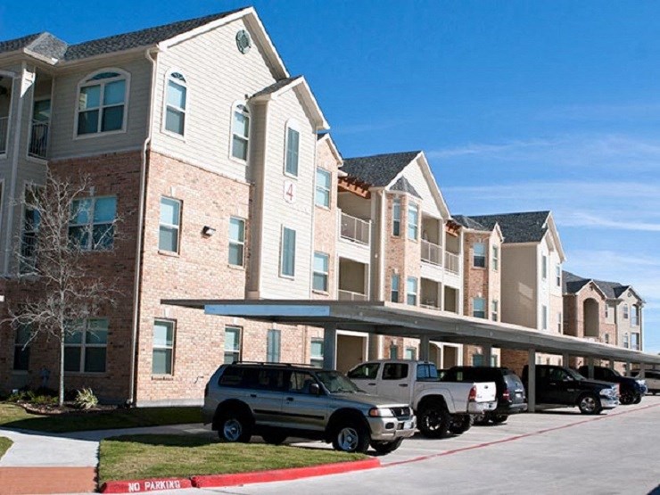 A row of cars are parked in a row in front of a building.
