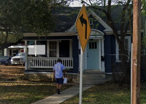 A yellow sign with a black arrow pointing to the left is in front of a house.