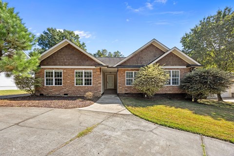 A house with a brown roof and a driveway in front.