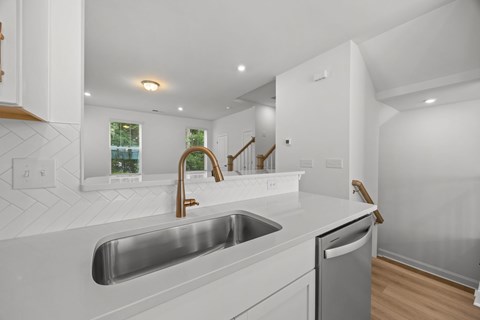 A modern kitchen with a stainless steel sink and wooden cabinets.