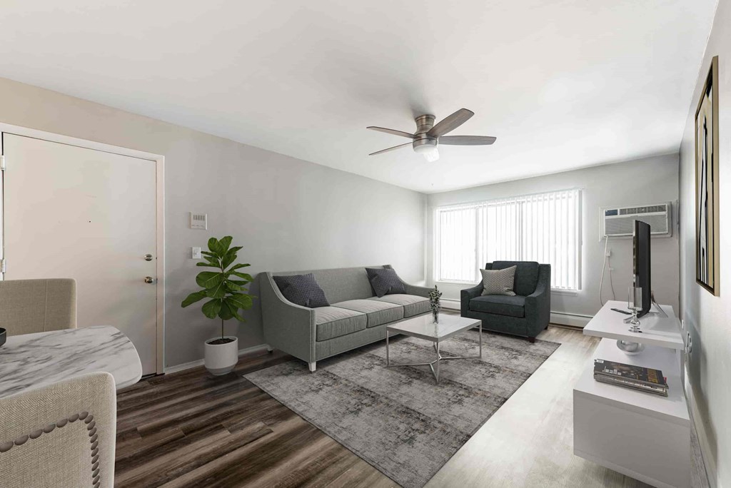 A living room with a grey couch, a white coffee table, and a ceiling fan.