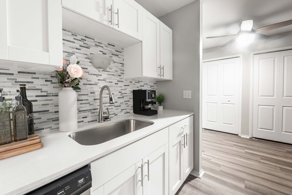 A modern kitchen with white cabinets and a stone backsplash.