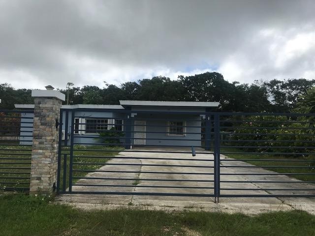 A house with a grey roof and a black gate in front of it.