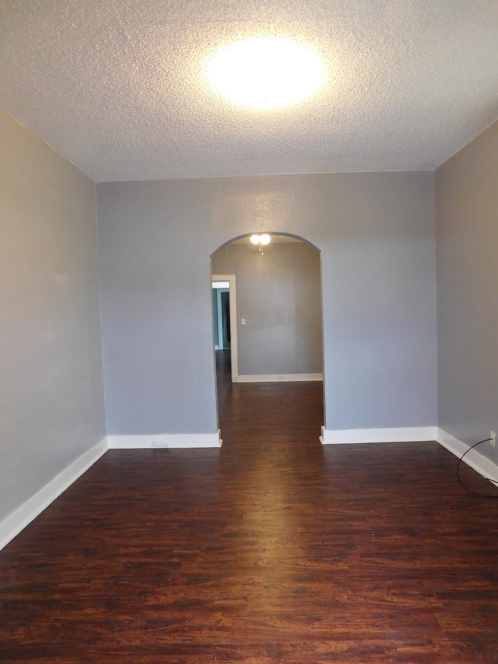 A hallway with wood floors and a white wall.