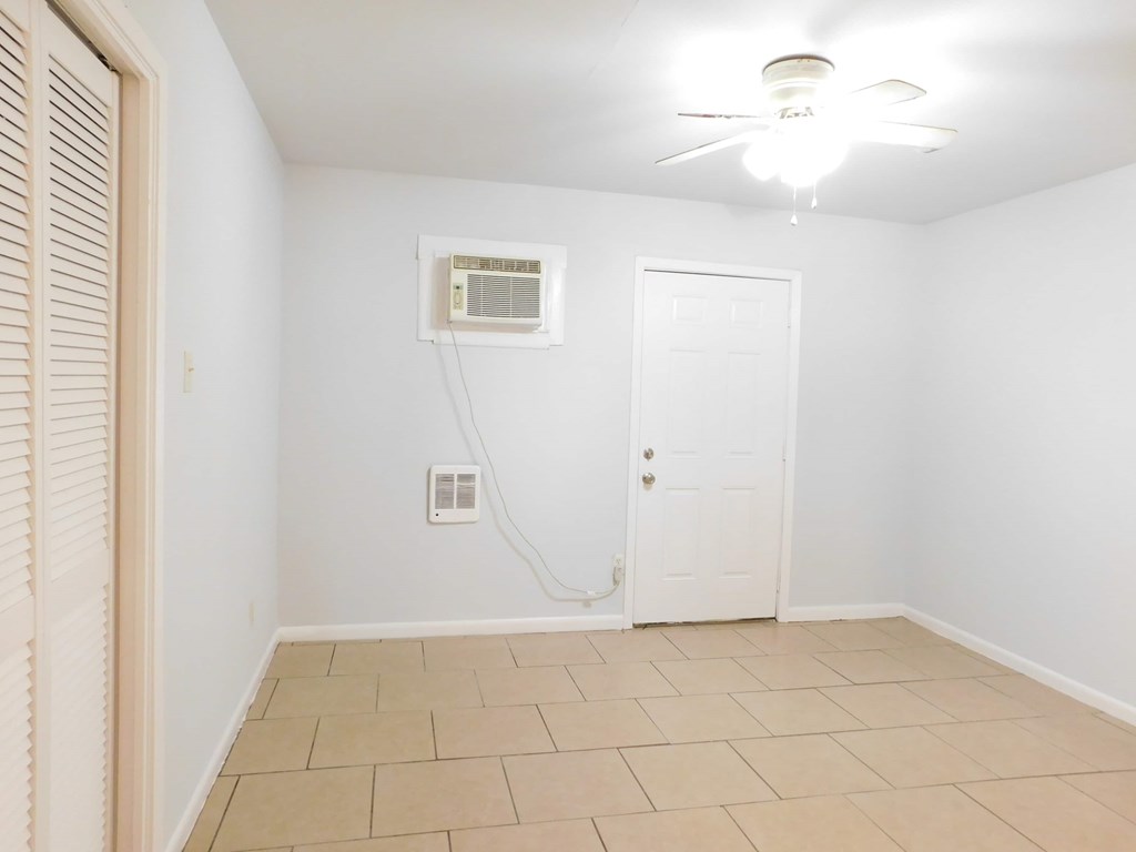 A room with a fan and a window with blinds.