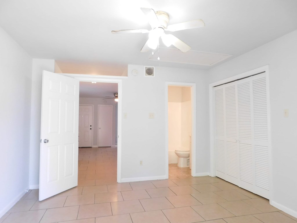 A room with a ceiling fan and tile flooring.