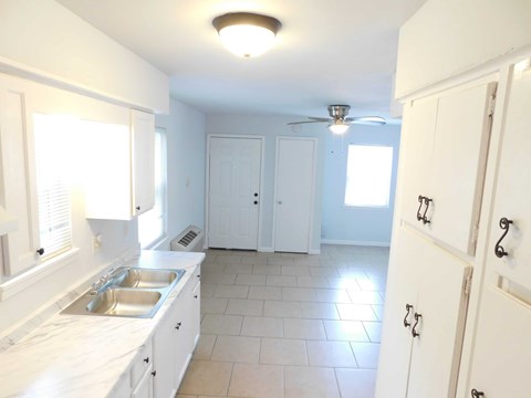A kitchen with white cabinets and a tile floor.