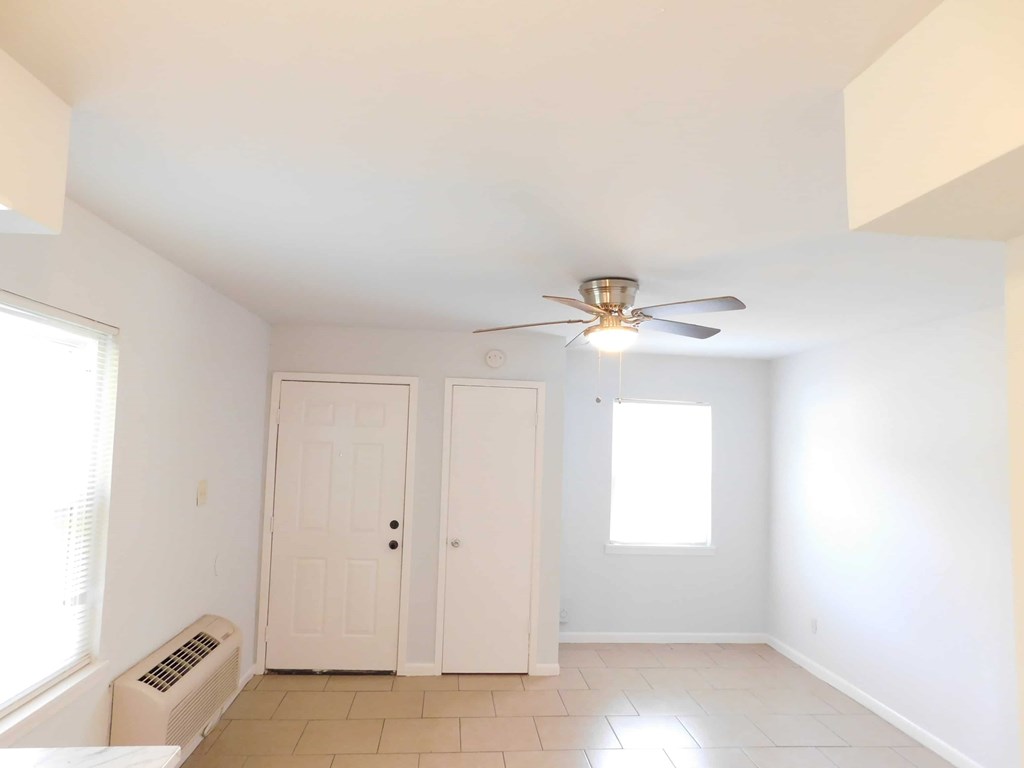 A room with a ceiling fan and two doors.