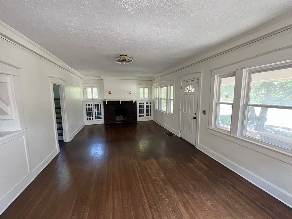 A long, empty room with wood floors and white walls.