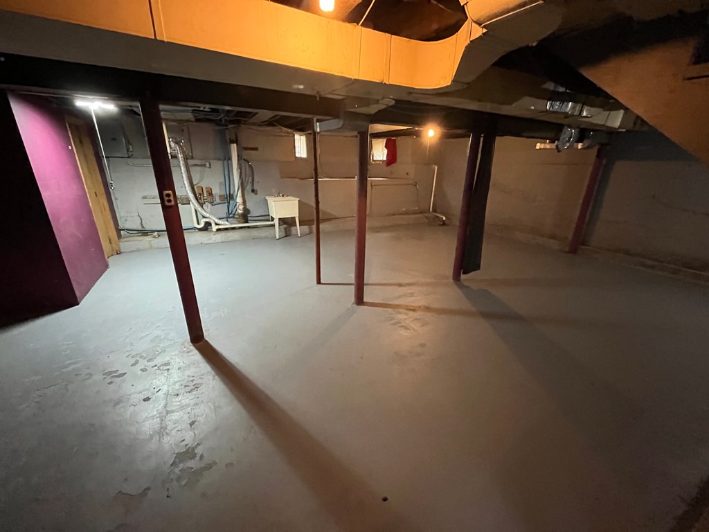 A large empty room with a concrete floor and a ceiling with exposed beams.