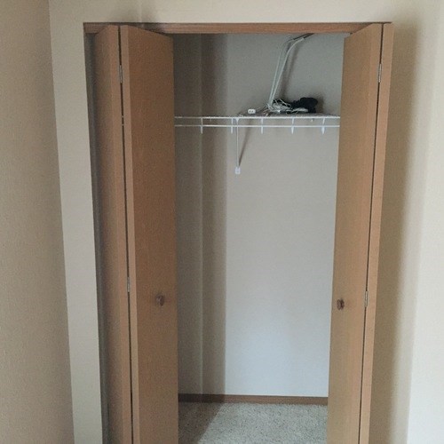 A white closet with a door open and a shelf with a few items on it.