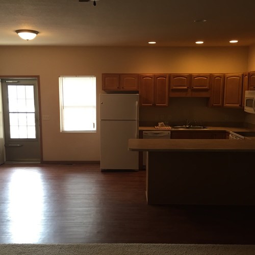 A kitchen with wooden floors and white appliances.