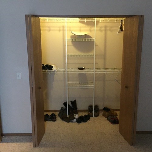 A pair of shoes are on the floor in front of a closet.
