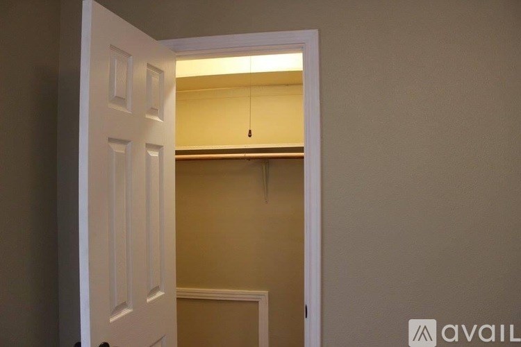 A white door is open to a small, empty room with a single light fixture.