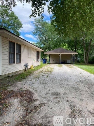 A house with a covered porch and a gravel driveway.