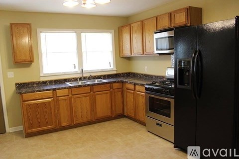 A kitchen with wooden cabinets and a black refrigerator.
