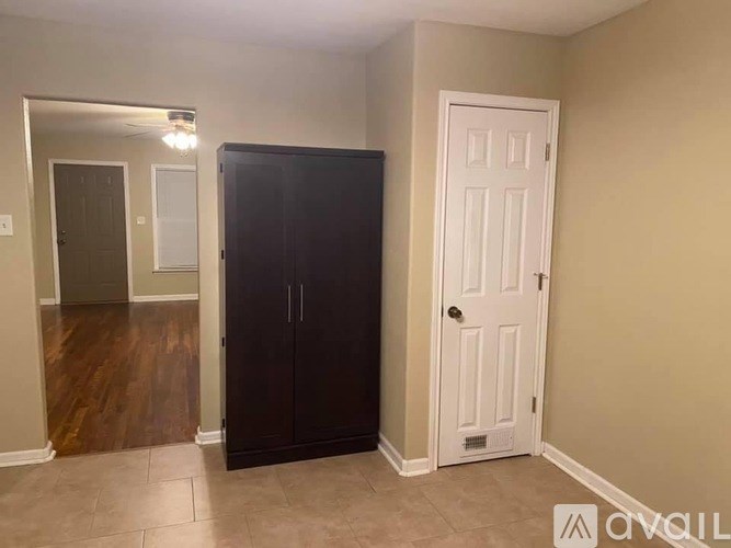 A black wardrobe stands in a room with a white door.