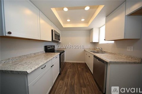 A kitchen with white cabinets and a granite countertop.