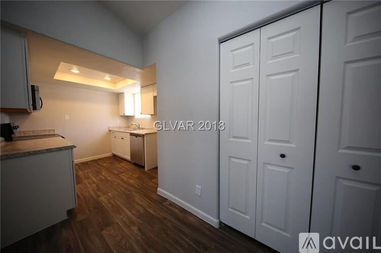 A kitchen with white cabinets and a wooden floor.