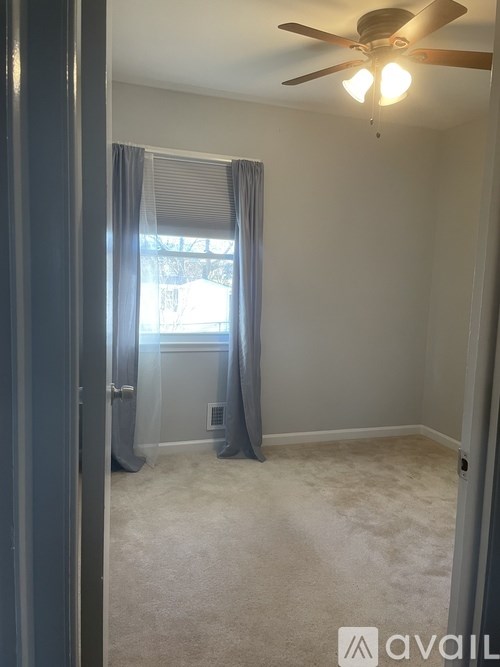 A room with a ceiling fan and carpeted floor.