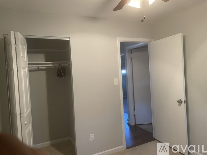 A room with a white door and a white ceiling fan.