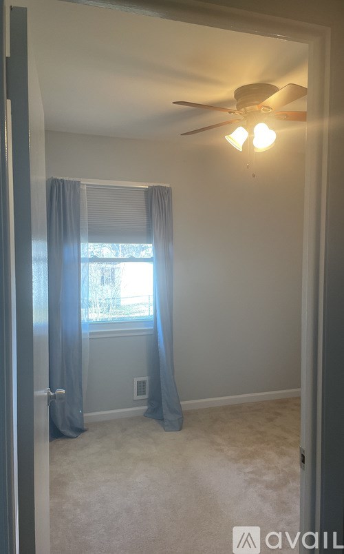 A room with a ceiling fan and carpeted floor.