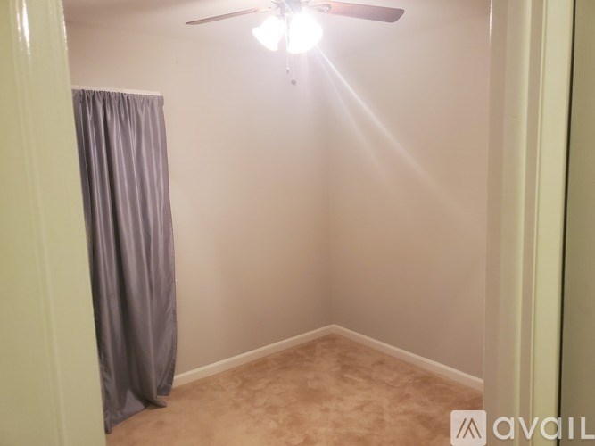 A room with a ceiling fan and a curtain.