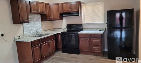 A kitchen with wooden cabinets and a black refrigerator.