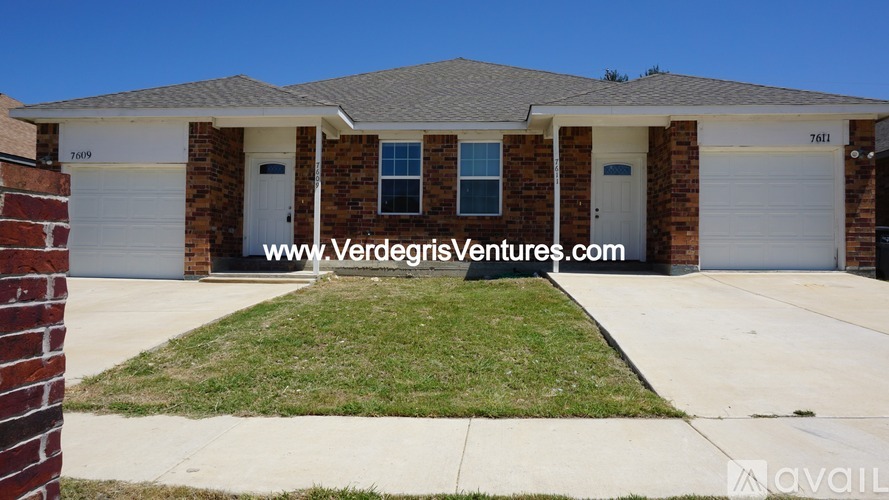 A house with a white garage door and a brick wall in front.