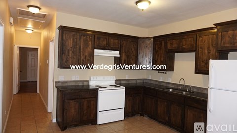 A kitchen with wooden cabinets and a white refrigerator is available for rent.