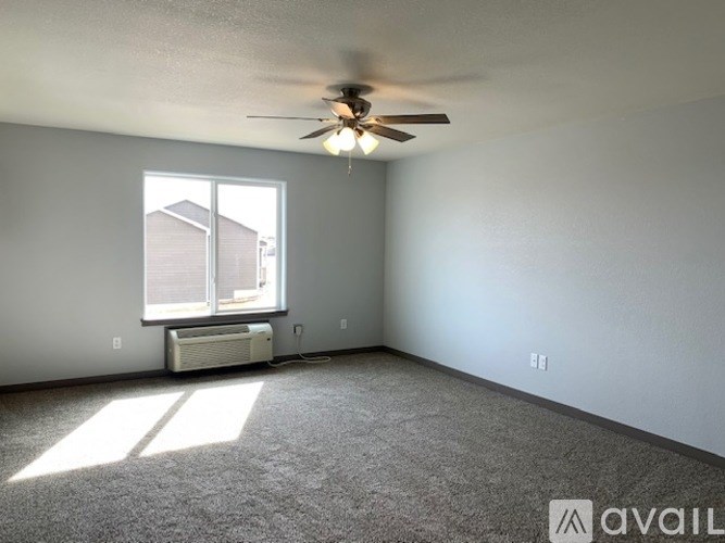 A room with a ceiling fan and a window with an air conditioner unit underneath it.
