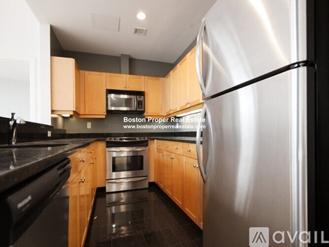 A modern kitchen with wooden cabinets and a stainless steel refrigerator.