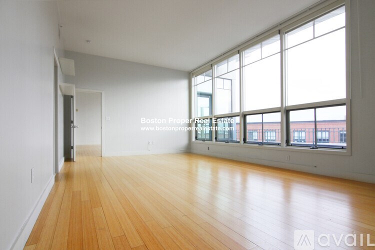 A large empty room with wooden floors and large windows.