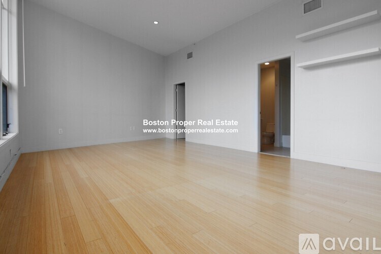 A large empty room with wooden floors and white walls.