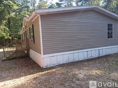 A small house with a porch and a window is surrounded by trees.