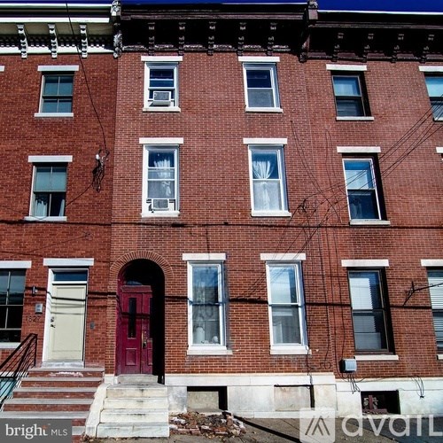A red door is on the front of a red brick building.