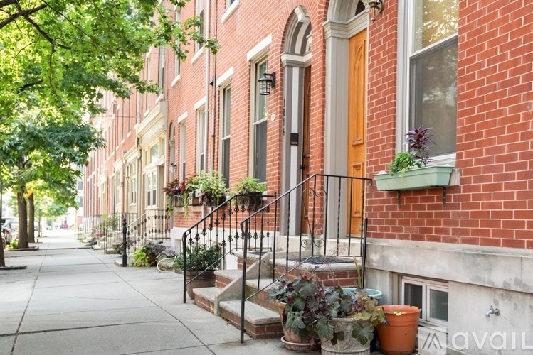 A row of red brick houses with green plants in front.