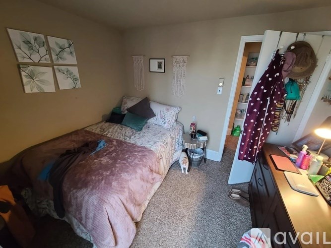 A bedroom with a bed covered in a pink blanket and a desk with a lamp on it.